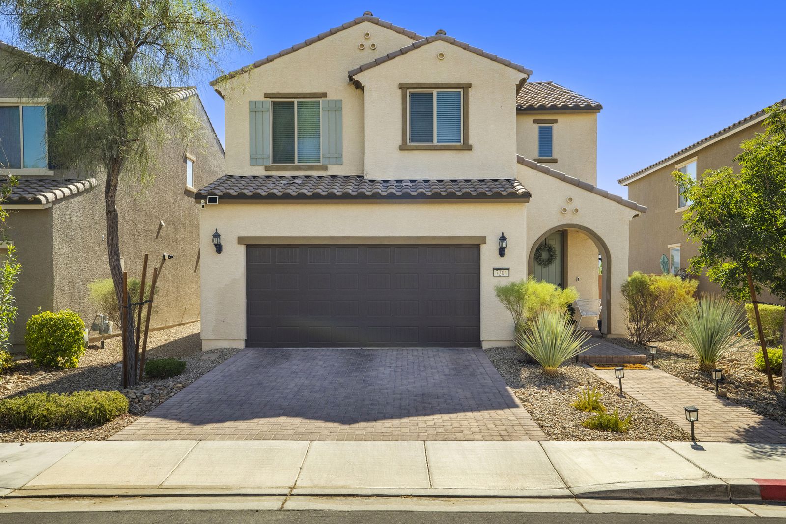 Front elevation of 7204 Site Street, a two story stucco home with a tile roof and a paver driveway.