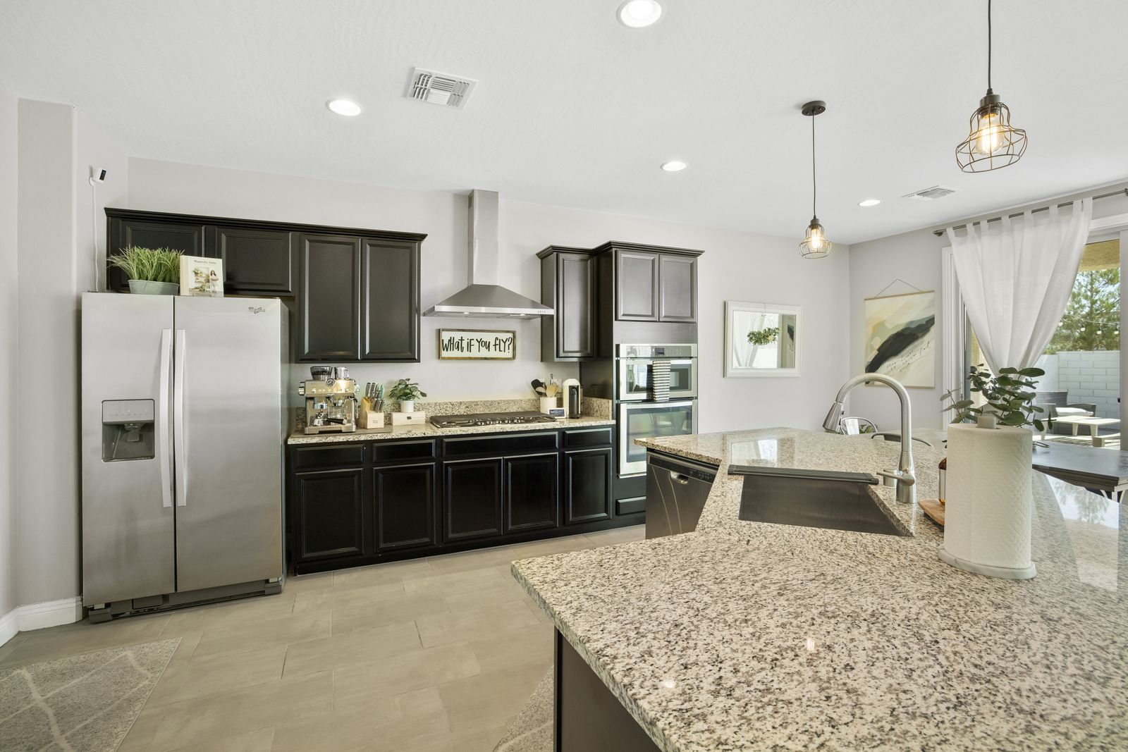 Gas cooktop, stainless double wall ovens, chimney hood, espresso cabinetry.