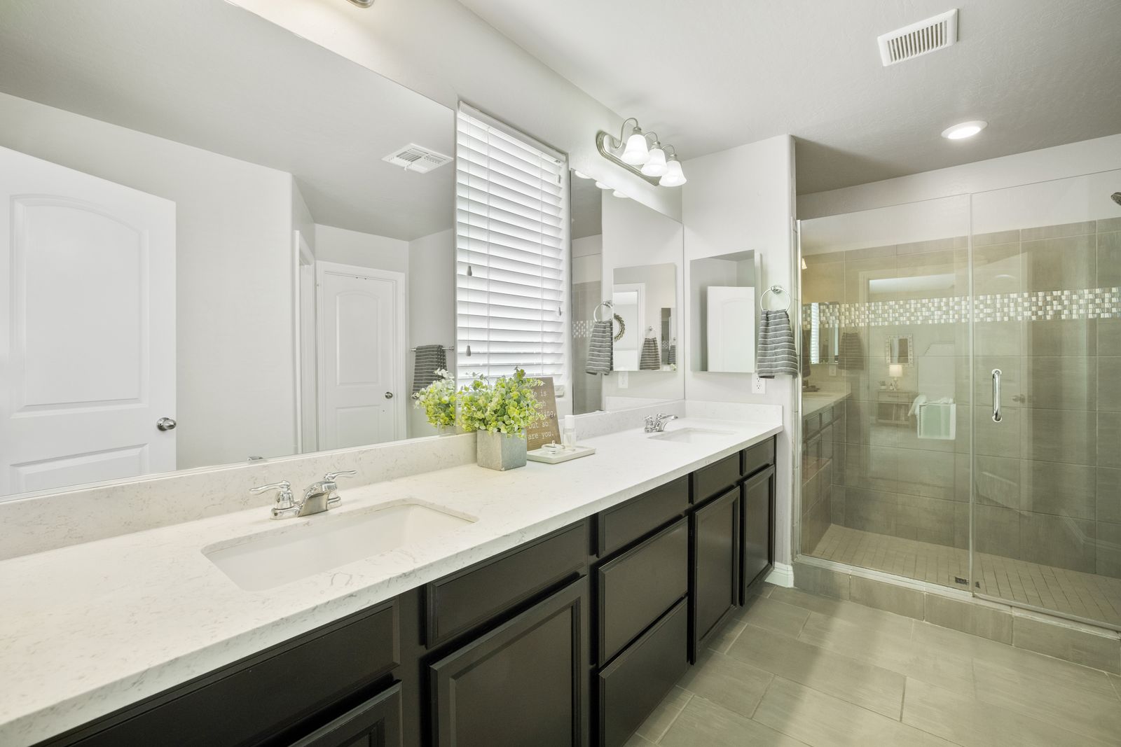 Primary bath. Dual vanities and a glass enclosed walk in shower with a tile inlay band.